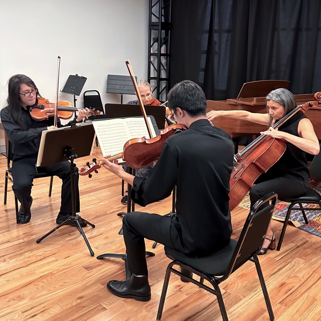 Photograph of a string quartet performing with a piano in the background